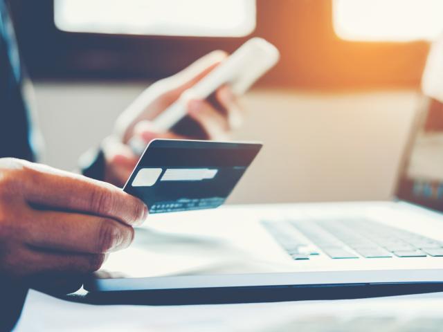 man holding credit card and laptop
